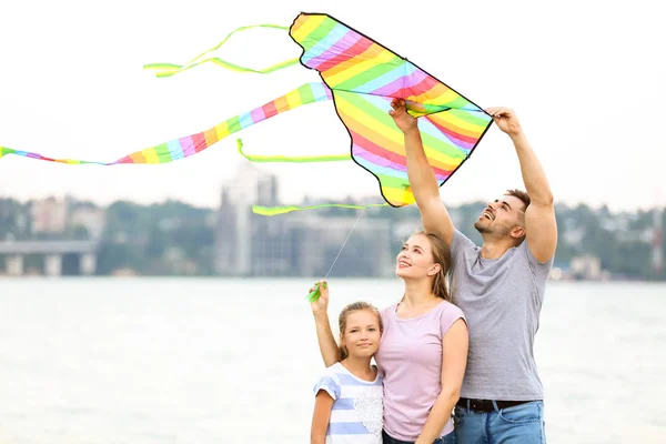 Happy family flying kite near river — Stock Photo, Image
