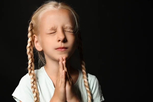 Little girl praying on dark background — Stock Photo, Image