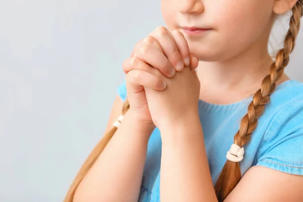 Little girl praying on light background, closeup — Stock Photo, Image