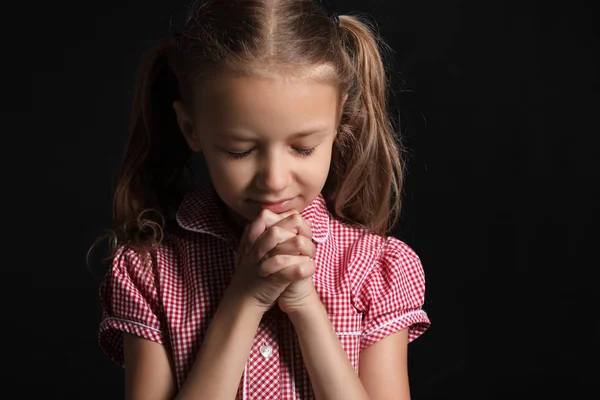 Praying little girl on dark background — Stock Photo, Image