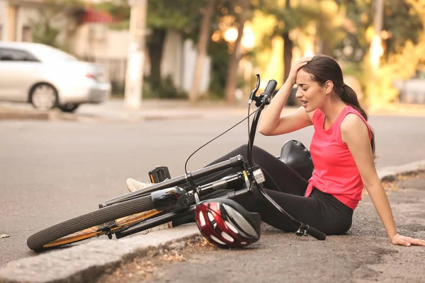 Sporty young woman fallen off her bicycle outdoors — Stock Photo, Image