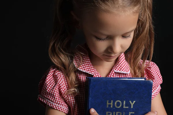 Χαριτωμένο μικρό κορίτσι με τη Βίβλο σε σκούρο φόντο — Φωτογραφία Αρχείου