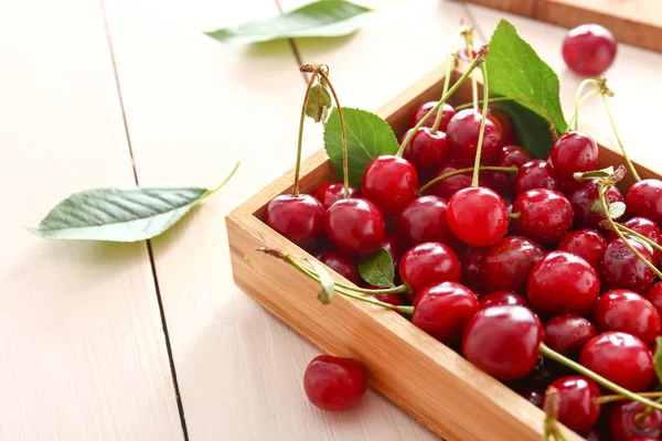 Box with ripe sweet cherry on wooden table