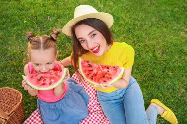 Sevimli küçük kız ve annesi parkta tatlı karpuz yeme