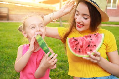 Sevimli küçük kız ve annesi parkta tatlı karpuz yeme