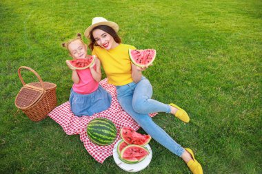 Sevimli küçük kız ve annesi parkta tatlı karpuz yeme