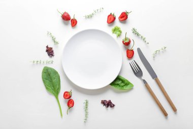 Beyaz arka plan üzerinde çatal bıçak takımı, çilek ve otlar ile Boş plaka