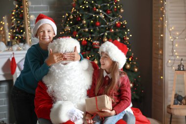 Noel Baba ve küçük çocuklar Noel için dekore odada oynuyor