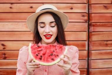 Ahşap arka plan üzerinde tatlı karpuz dilim ile güzel genç kadın