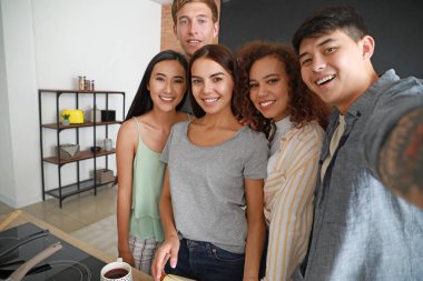 Mutlu arkadaşlar mutfakta birlikte yemek yaparken selfie çekiyor