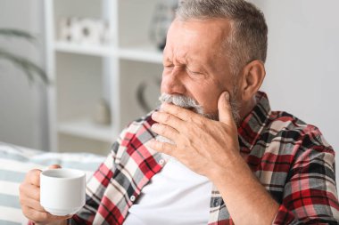 Evde hassas dişleri ve bir fincan sıcak kahve ile Kıdemli adam