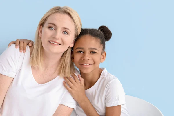 Happy woman with her African-American daughter on color background — Stock Photo, Image