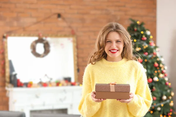 Happy young woman with Christmas gift at home — Stock Photo, Image