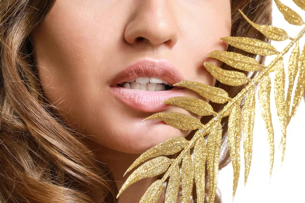Mooie jonge vrouw met gouden tropische blad op witte achtergrond, close-up — Stockfoto