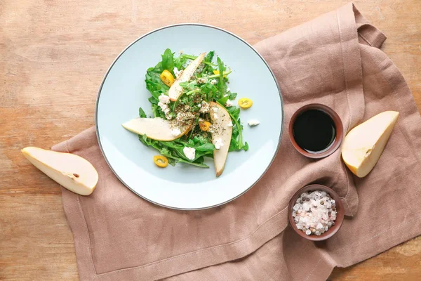 Plate with tasty arugula salad on wooden background — Stock Photo, Image