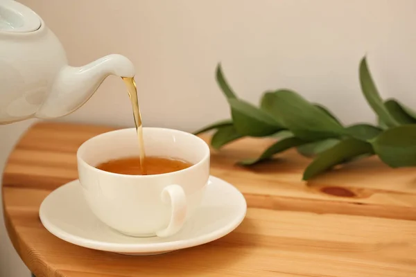 Наливание горячего чая в чашку на стол — стоковое фото