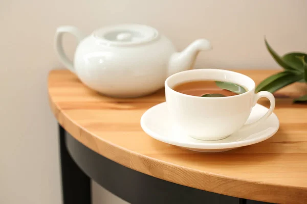 Tasse Heißgetränk und Teekanne auf dem Tisch — Stockfoto