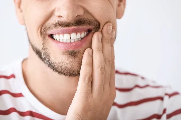 Man die lijdt aan kiespijn tegen lichte achtergrond, close-up — Stockfoto