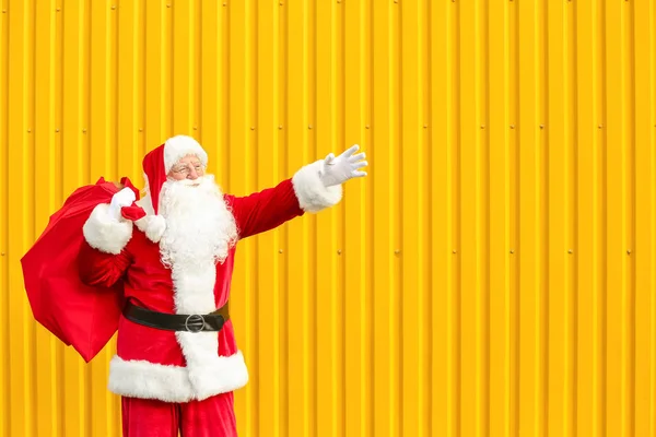 Weihnachtsmann mit Geschenken in Tüte auf farbigem Hintergrund — Stockfoto