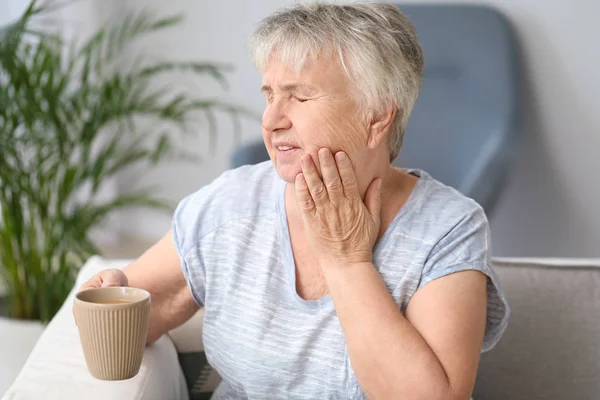 Senior woman with sensitive teeth and cup of hot coffee at home — Stock Photo, Image