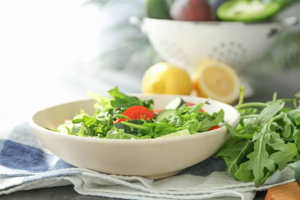 Tigela com salada de rúcula saborosa na mesa — Fotografia de Stock