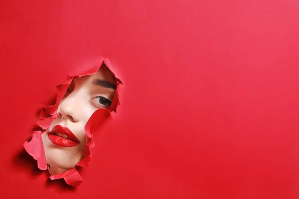 Rosto da bela jovem visível através de buraco em papel colorido — Fotografia de Stock