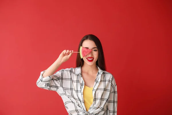 Schöne junge Frau mit Scheibe frischer Wassermelone auf farbigem Hintergrund — Stockfoto