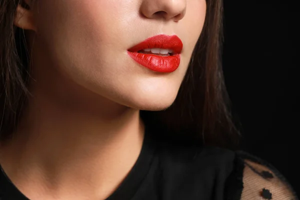 Beautiful young woman with bright lipstick on dark background, closeup — Stock Photo, Image