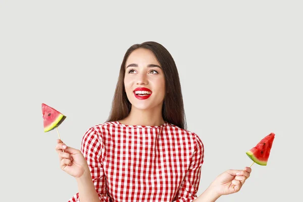 Schöne junge Frau mit Scheiben frischer Wassermelone auf hellem Hintergrund — Stockfoto