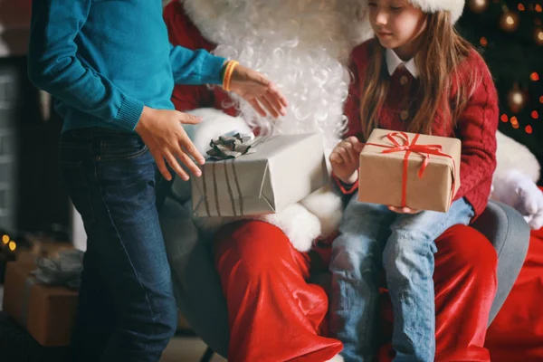 Weihnachtsmann und kleine Kinder mit Geschenken im weihnachtlich dekorierten Zimmer — Stockfoto