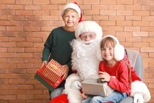 Santa Claus and little children with gifts near brick wall — Stock Photo, Image