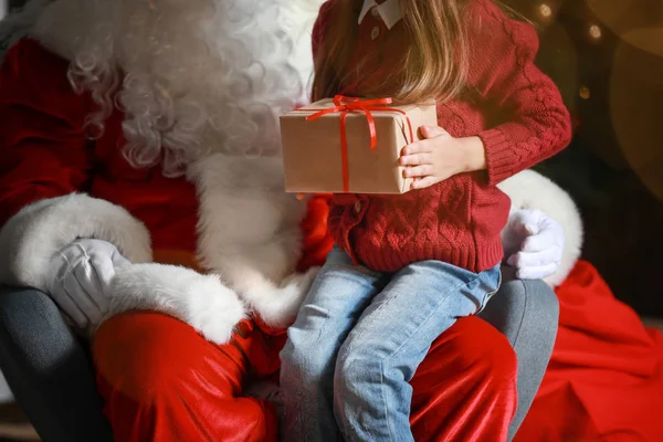 Santa Claus and little girl with gift in room decorated for Christmas — Stock Photo, Image