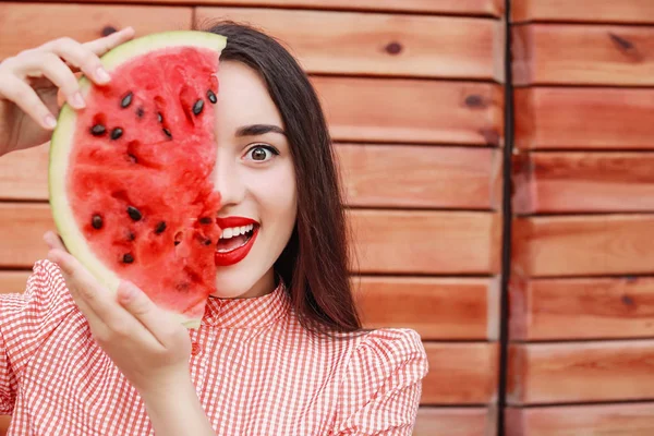 Beautiful young woman with slice of fresh watermelon on wooden background — Stock Photo, Image