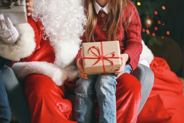 Jultomten och liten flicka med gåva i rummet dekorerad för julen — Stockfoto