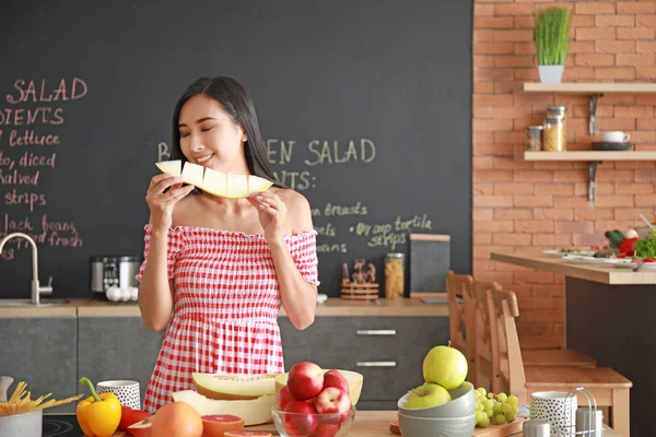 Güzel Asyalı kadın mutfakta lezzetli kavun yeme