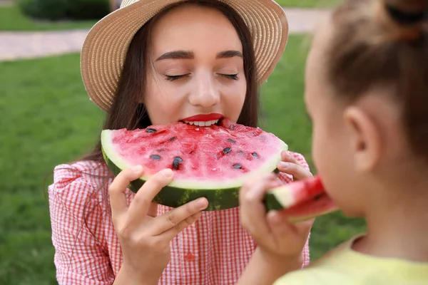 Cute little girl and her mother eating sweet watermelon in park — Stock Photo, Image