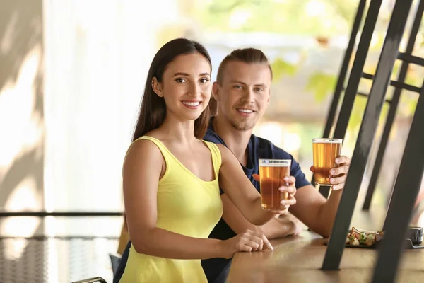 Young couple drinking fresh beer in pub — Stock Photo, Image