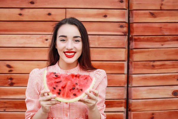 Beautiful young woman with slice of fresh watermelon on wooden background — Stock Photo, Image