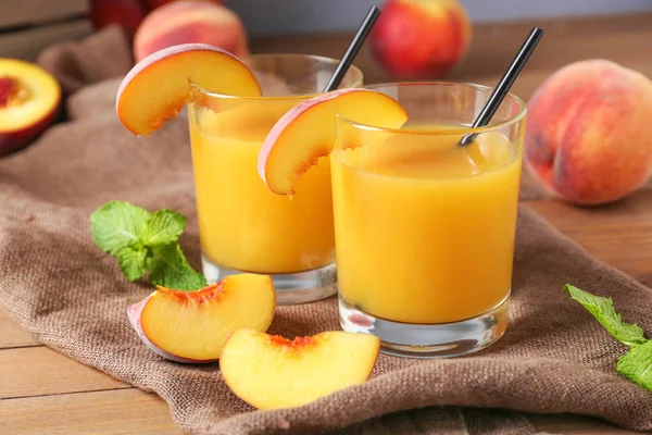 Glasses of tasty peach juice on wooden table — Stock Photo, Image