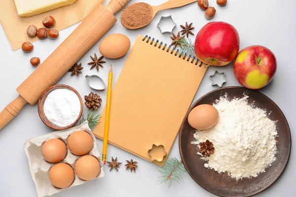 Notebook with cookie cutters and ingredients on white background — Stock Photo, Image