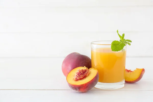 Glass of tasty peach juice on white wooden table — Stock Photo, Image