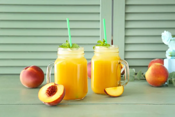 Mason jars of tasty peach juice on wooden table — Stock Photo, Image