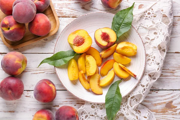 Тарілка зі смачними персиками на білому столі — стокове фото