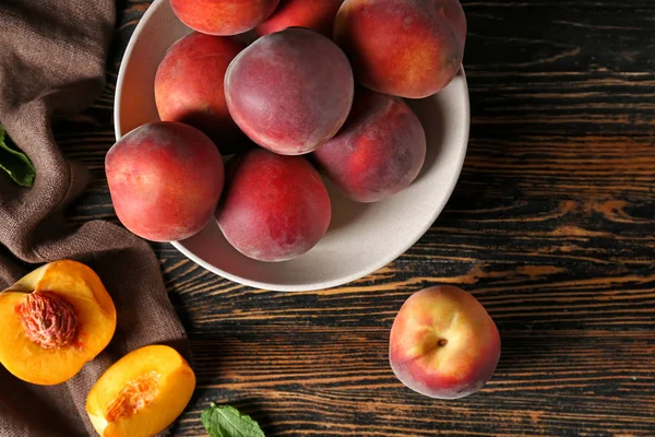 Миска зі смачними персиками на дерев'яному столі — стокове фото