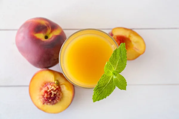 Glass of tasty peach juice on white wooden table — Stock Photo, Image