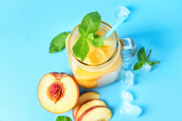 Mason jar of tasty peach juice on color background