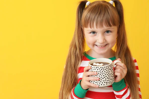 Cute little girl drinking hot chocolate on color background — Stock Photo, Image