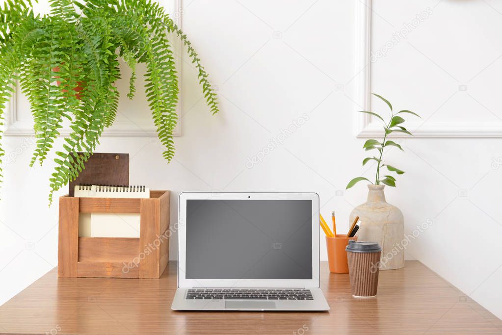 Stylish workplace with modern laptop near white wall