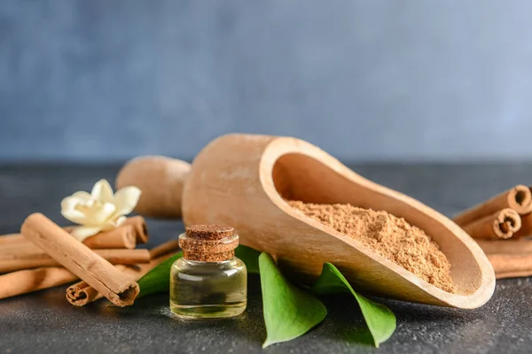 Scoop with cinnamon powder, essential oil and sticks on table — Stock Photo, Image