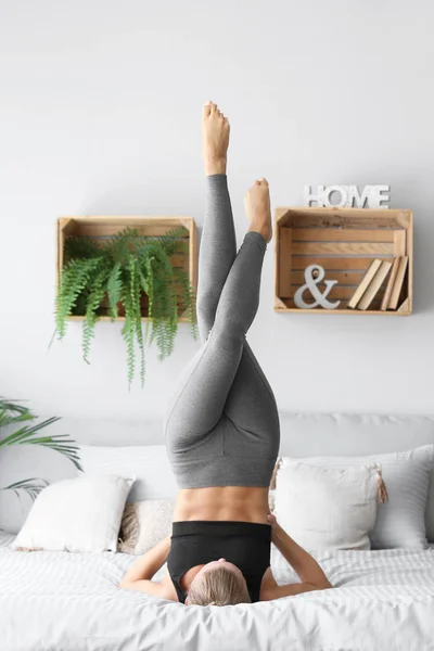 Young woman practicing yoga on bed at home — Stock Photo, Image